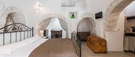 A bedroom with a bed, a wooden chest, and a dining area with a table and chairs.