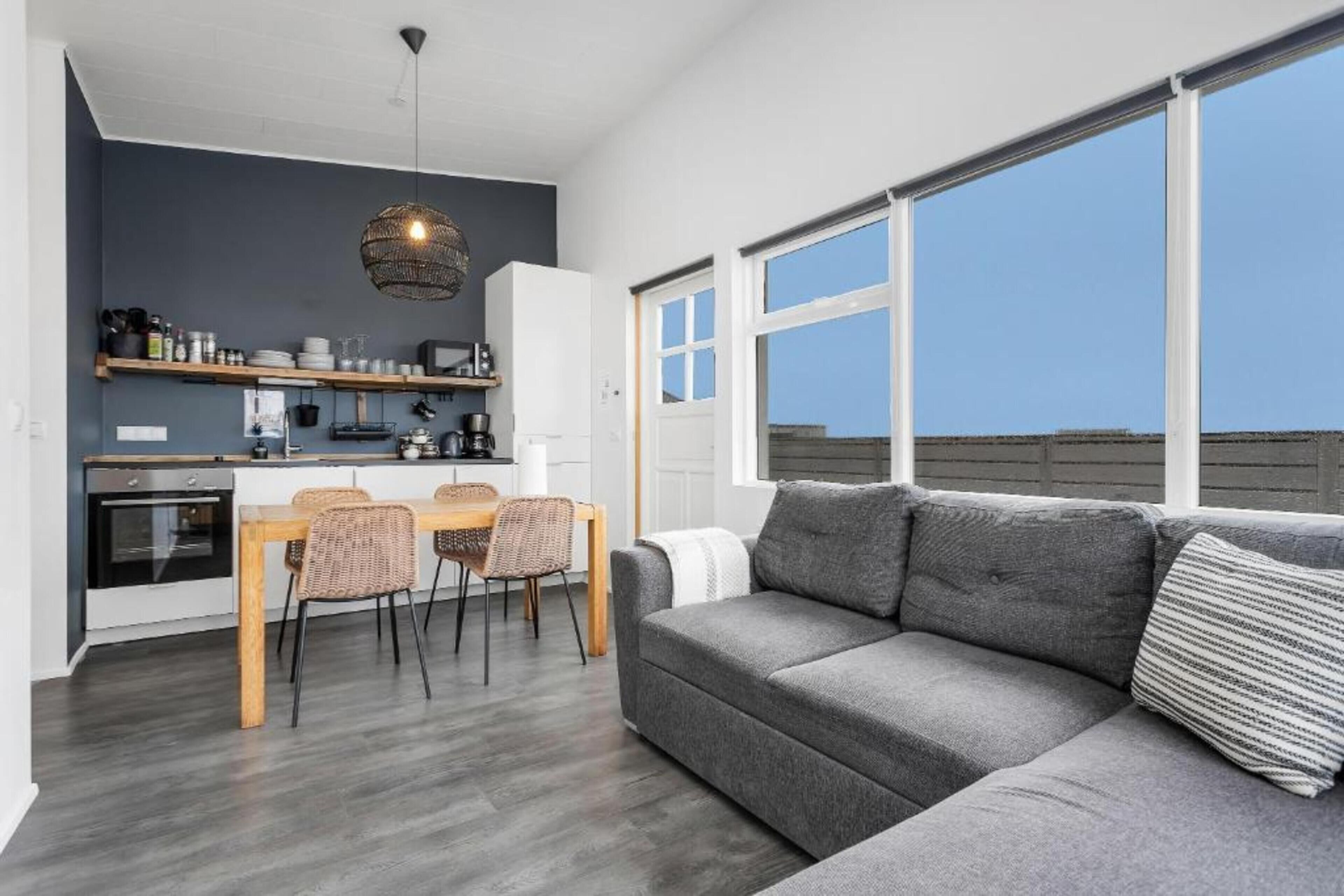 A modern apartment with a kitchen, dining area, and a large window.