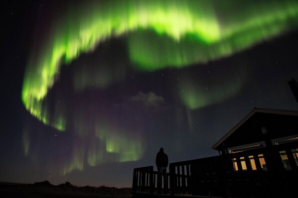 A house with a deck overlooking a night sky with the Northern Lights. - Ocean Break Cabins (Suðurnesjabær)