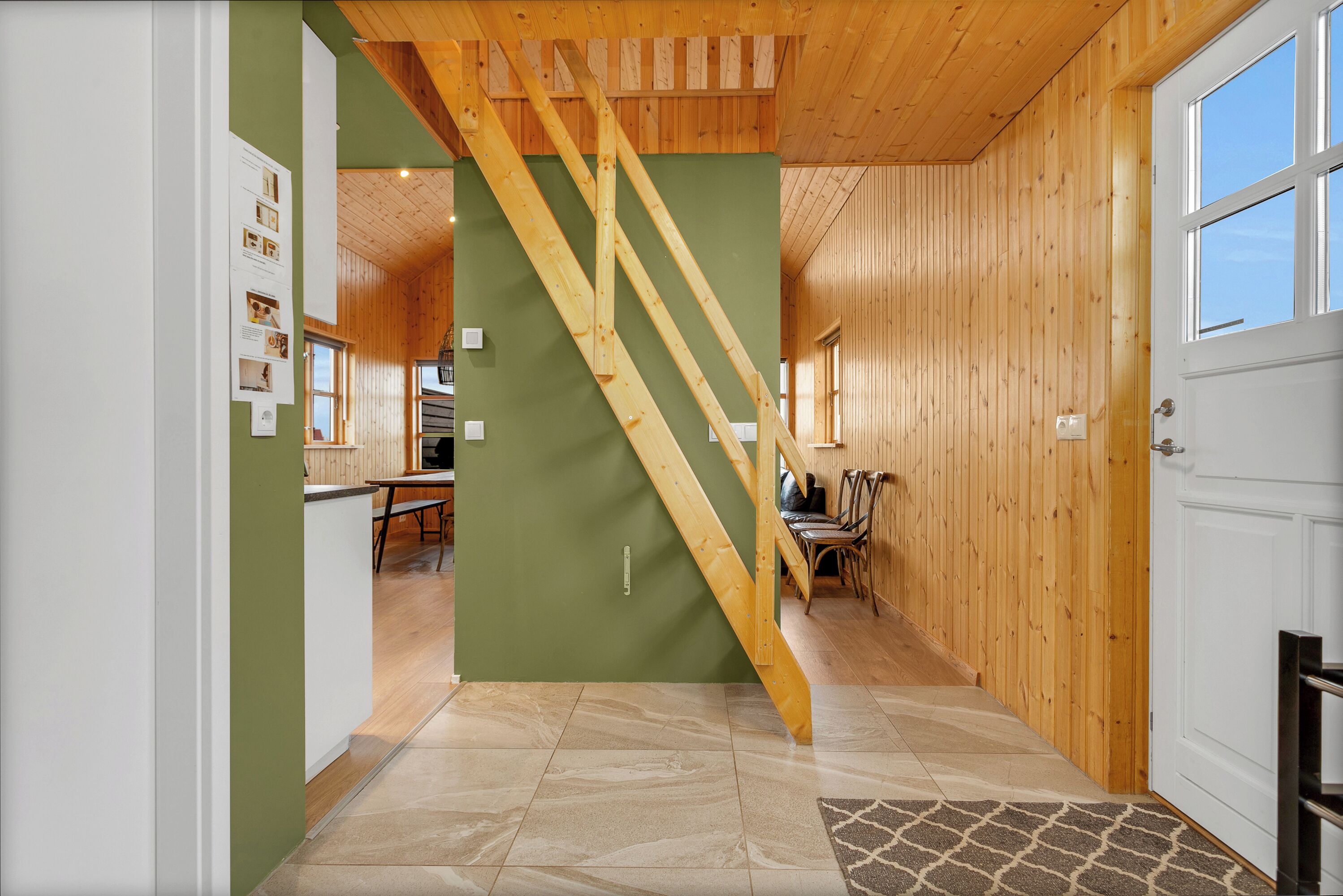 Un interior de madera con una escalera, un comedor y una cocina.
