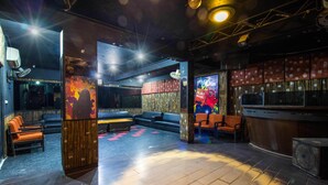 Una zona de bar con asientos, un escenario y una cabina para DJ.