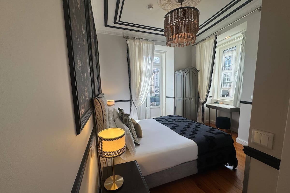 Une chambre à coucher comprenant un lit, une table de chevet, une lampe, une armoire et une vue sur la ville par la fenêtre.