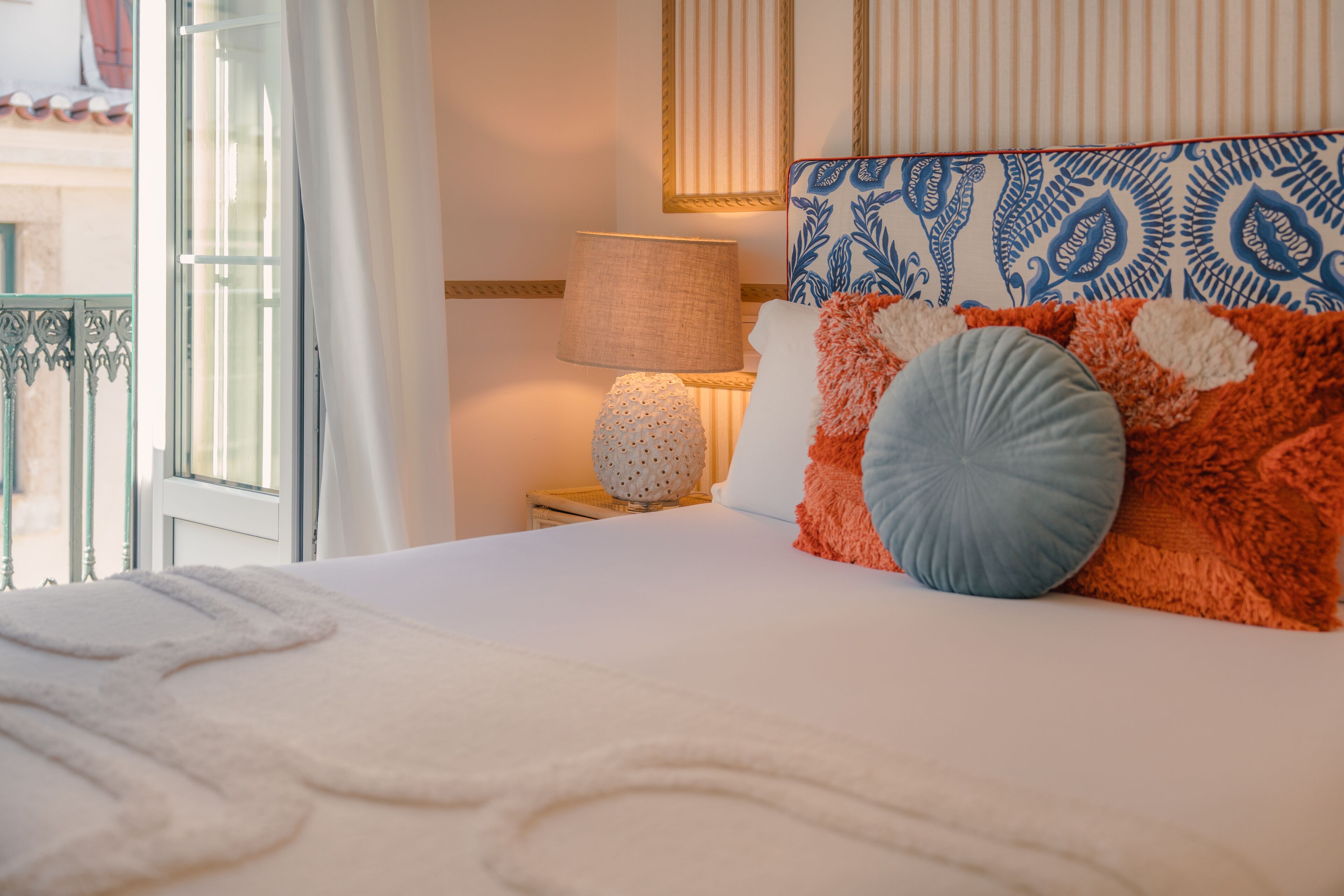 A neatly made bed with a white comforter, a patterned headboard, and decorative pillows.
