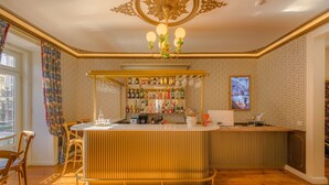 A bar area with a wooden bar counter, a chandelier, and a wall of liquor bottles. - Solar dos Poetas (Lisbon)