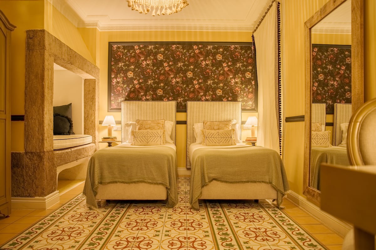 Une chambre avec deux lits, un grand miroir et un sol à motifs.