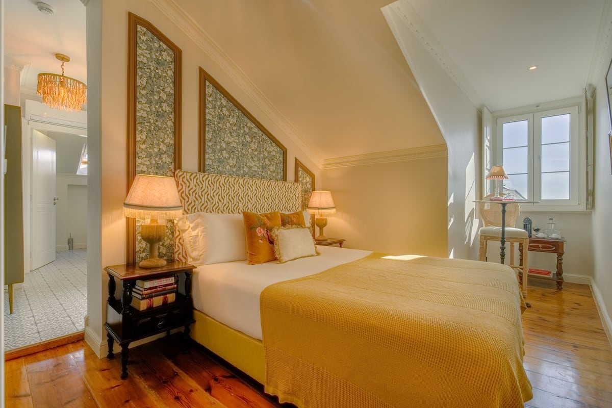 Une chambre à coucher avec un grand lit, deux lampes de chevet, une table de chevet avec des livres et une fenêtre donnant sur un beau paysage.