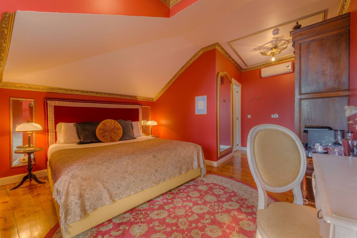 Une chambre à coucher avec un grand lit, une chaise, un bureau et un miroir.