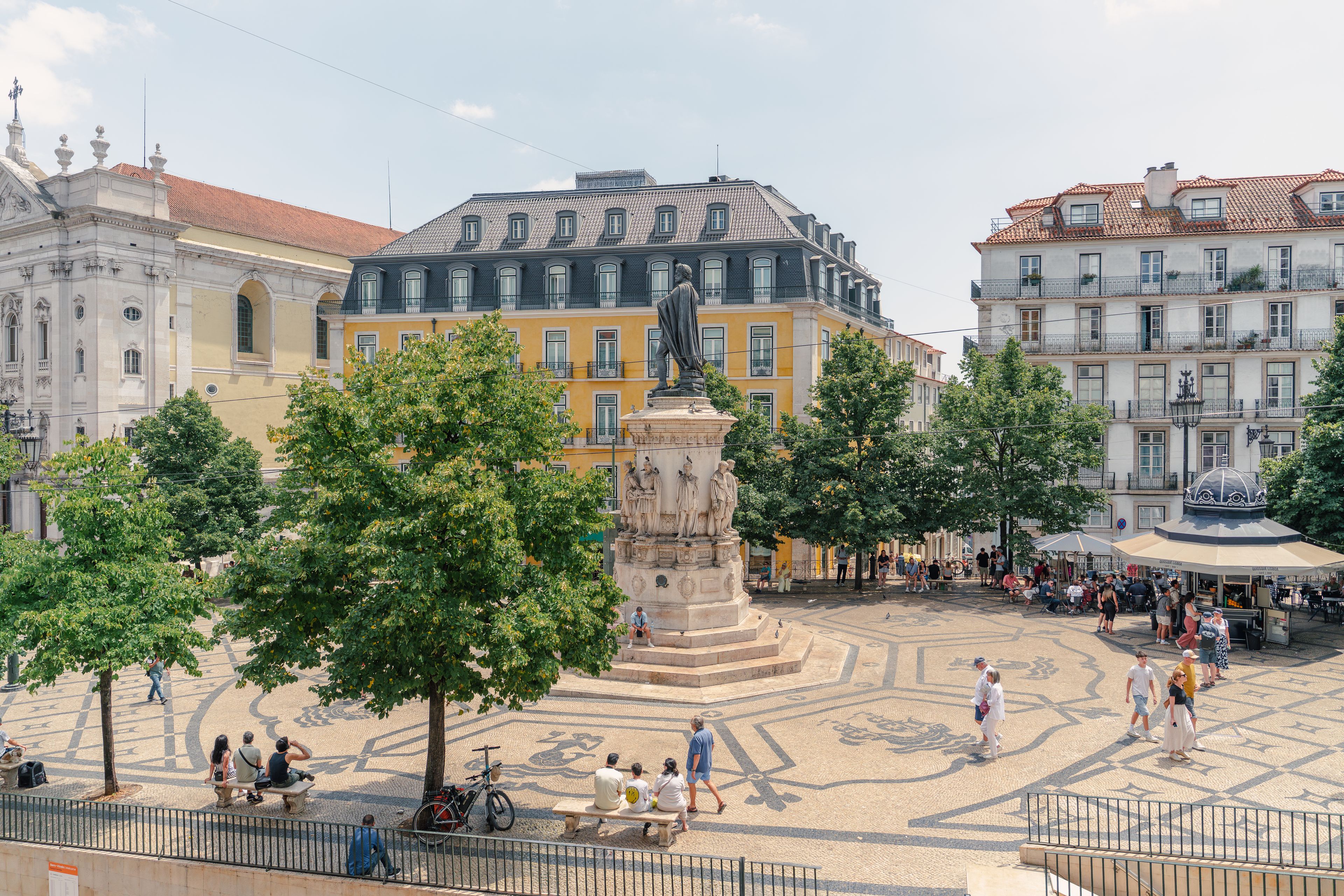 A public square with a central monument, surrounded by historic buildings and trees.