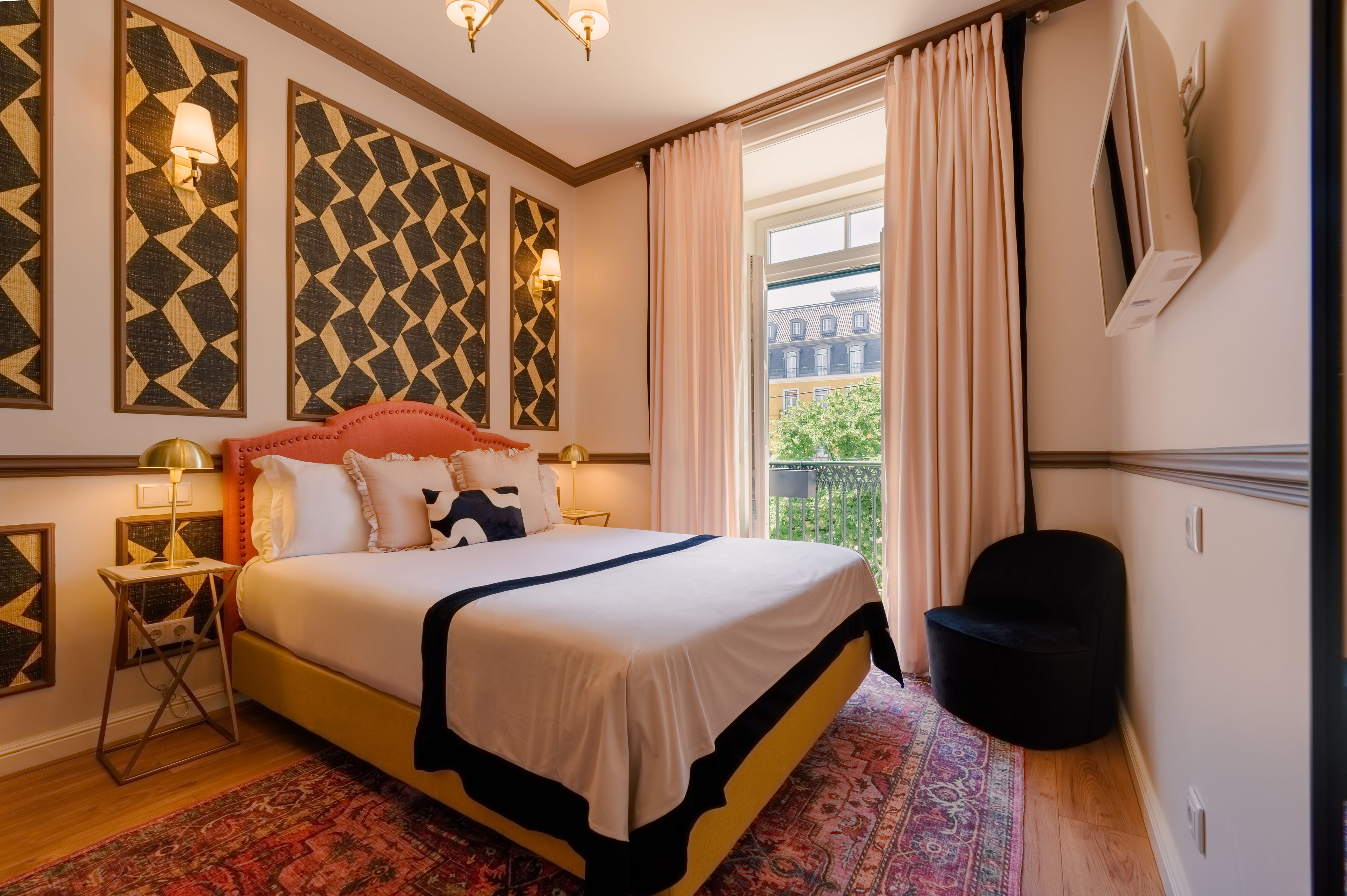 A hotel room with a large bed, a view of the city through the window, and a balcony.