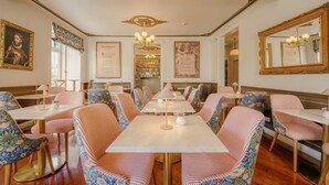 A dining area with striped upholstered chairs, tables, and a chandelier. - Solar dos Poetas (Lisbon)