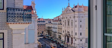 A street view with historic buildings, a tram, and a clear blue sky.