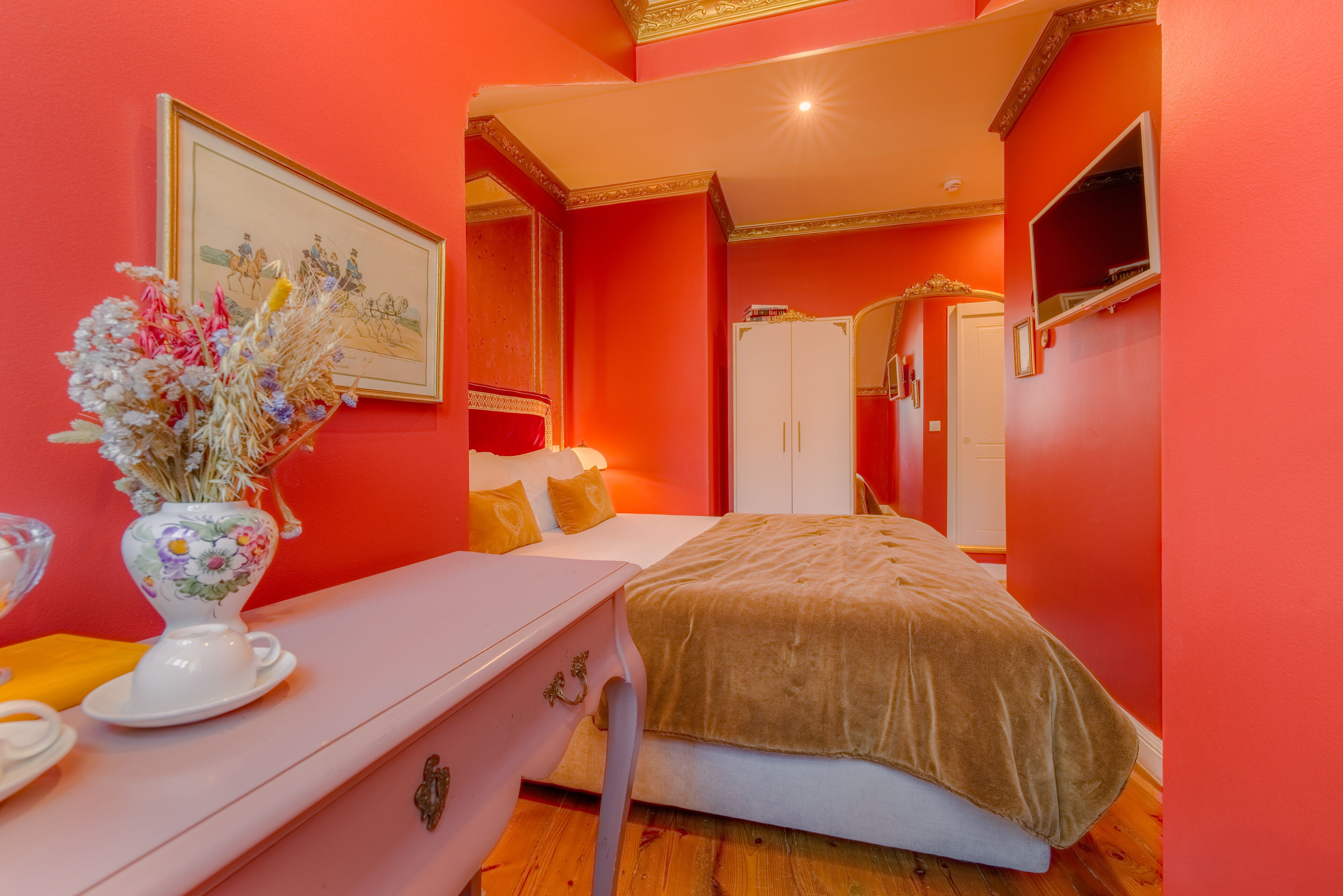 A bedroom with a bed, a dresser, a mirror, and a framed picture on the wall.