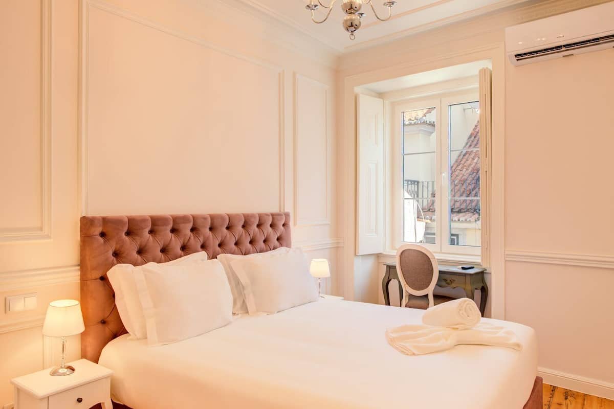 Une chambre à coucher bien aménagée, avec un grand lit, une table de chevet, une chaise et une fenêtre donnant sur un beau paysage.