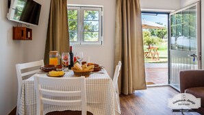 Comedor con una mesa lista para el desayuno, un televisor en la pared y vistas al exterior.