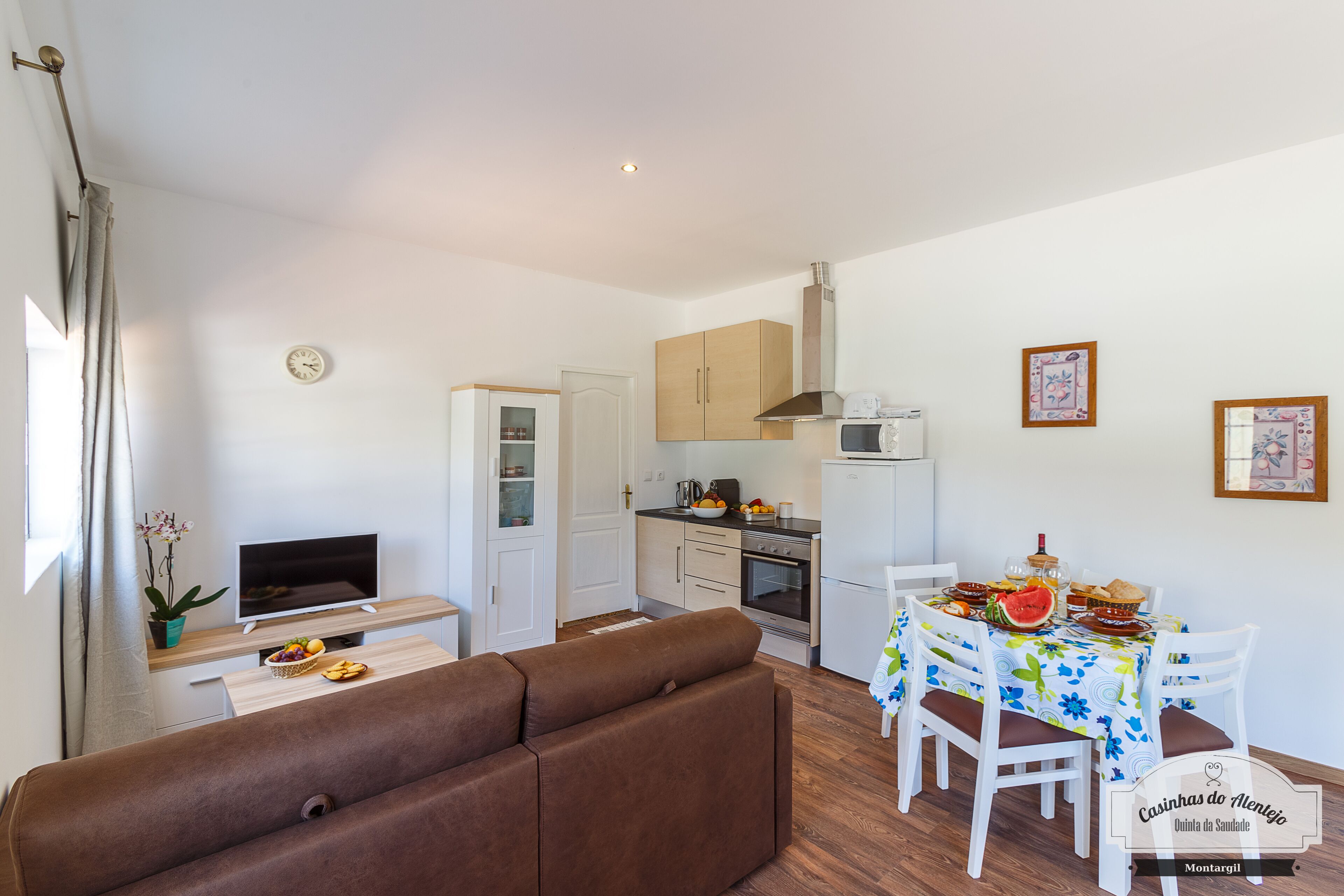 A compact living space with a sofa, dining table, kitchen area, and a TV.