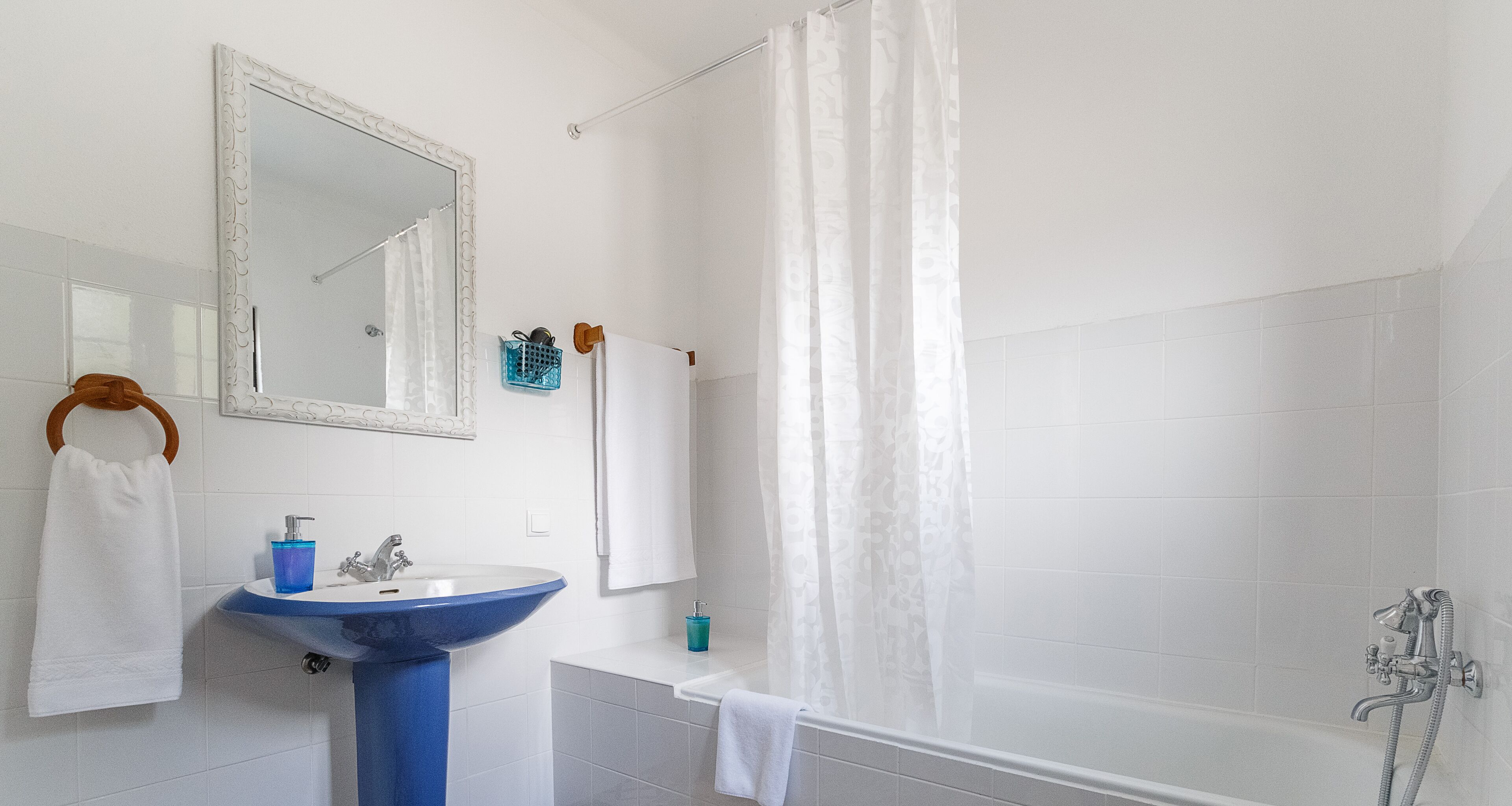 A bathroom with a white sink, mirror, and bathtub.