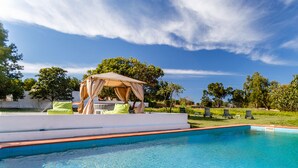 Una piscina con una pérgola y sillas de descanso.