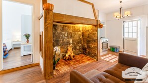 Una sala de estar acogedora con chimenea, piso de madera, un sofá y un comedor con mesa y sillas.