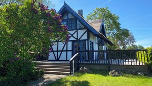 Een huis in traditionele Tudostijl, met een steile puntige kap, een opvallende schoorsteen en een houten trap naar de ingang.