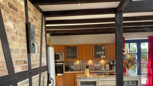 Een moderne keuken met zichtbare balken, een centraal eiland en een bakstenen muur.