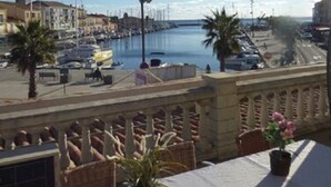 Vista para o mar a partir de uma varanda com mesa, cadeiras e um vaso de planta.