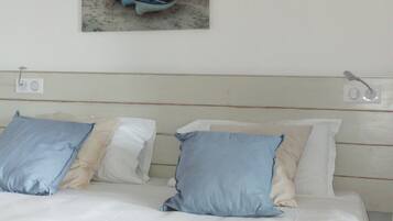 A bed with white bedding and two pillows, one blue and one beige.