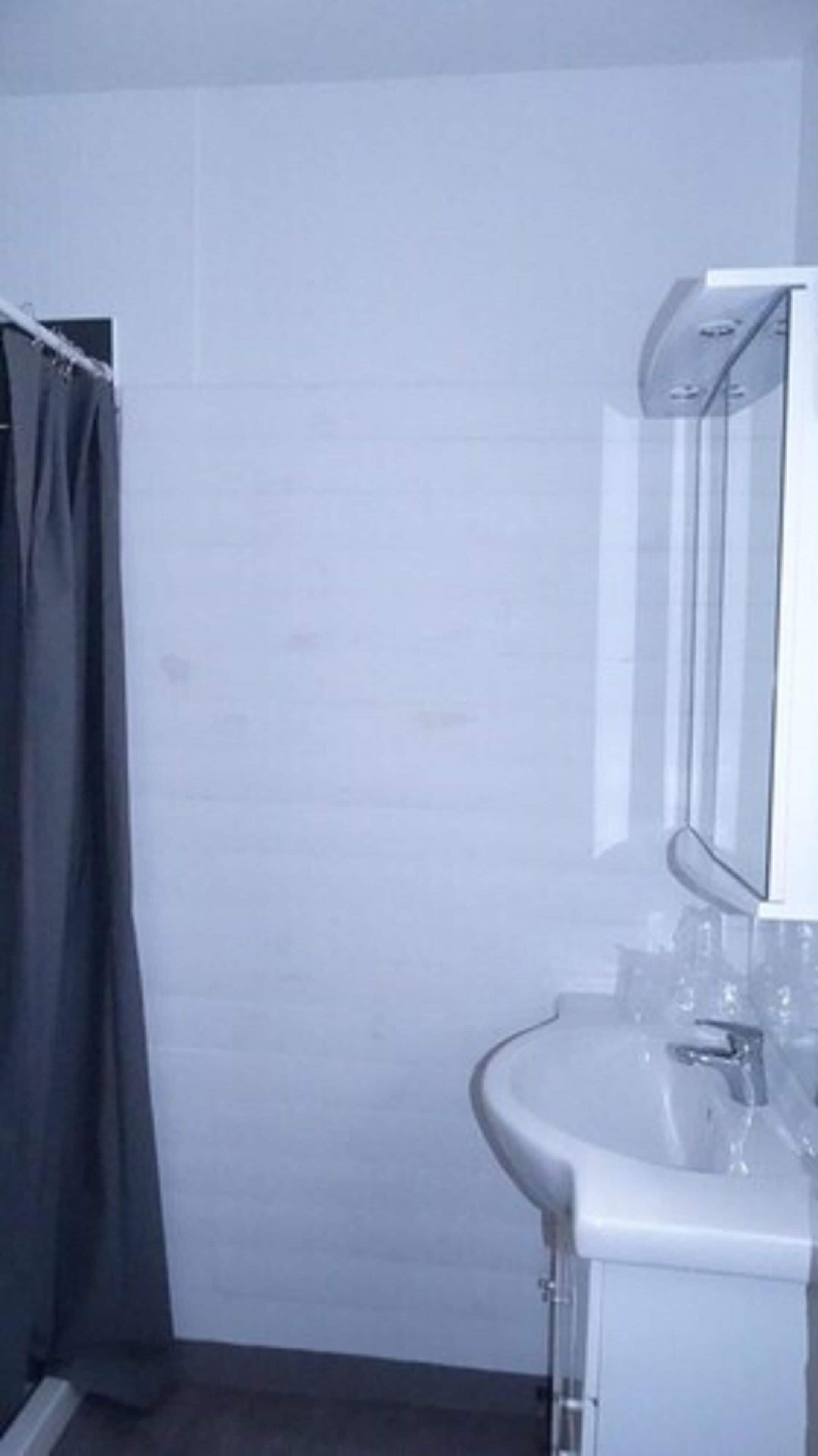A bathroom with a white sink, a mirror, and a shower curtain.
