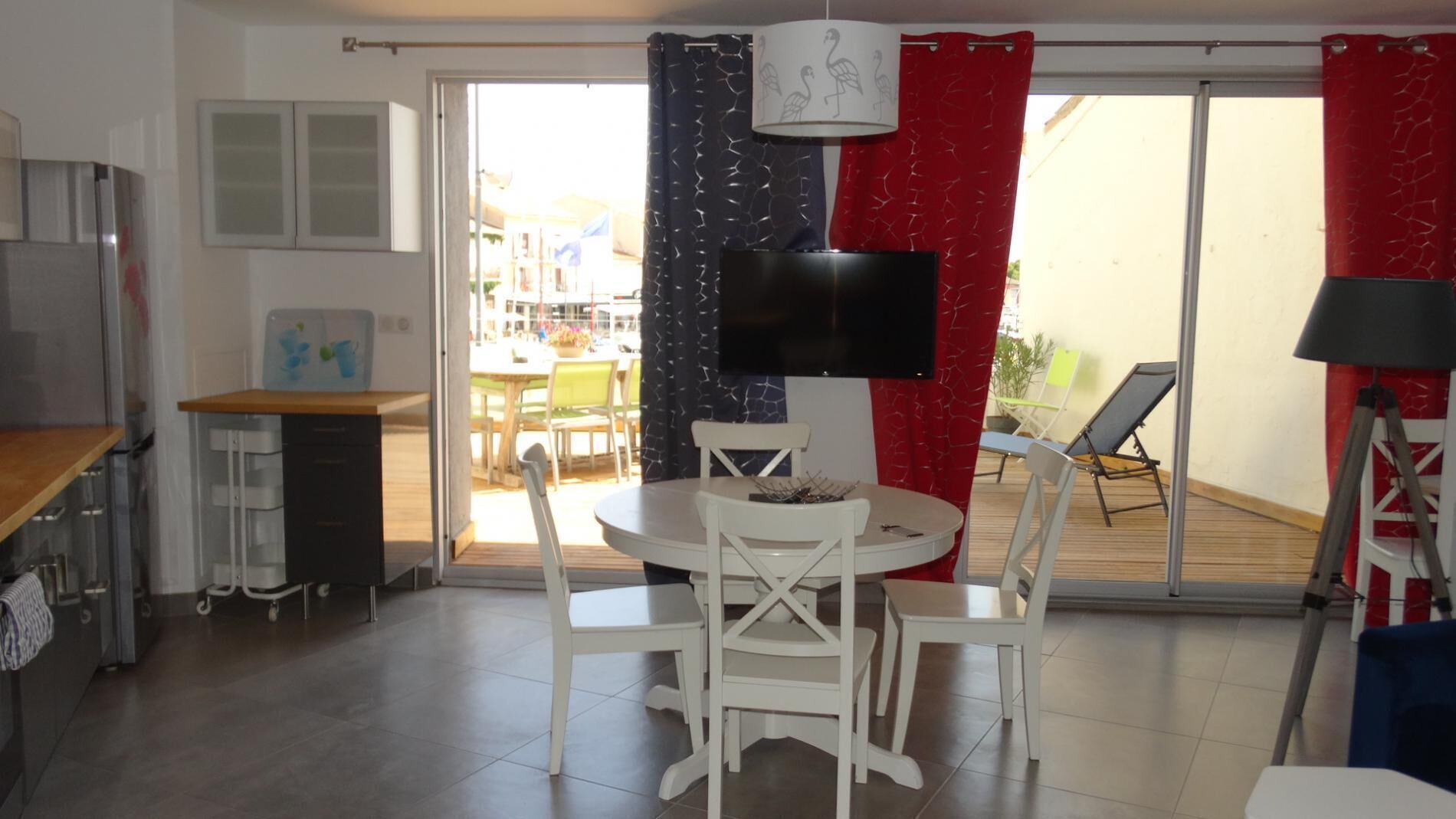 Ein kompakter Wohnbereich mit Essplatz, einem an der Wand befestigten Fernseher und einer Glastür zum Außenbereich.
