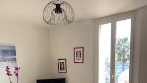 Uma sala de estar com área de jantar, televisão e uma grande janela com vista para o mar.