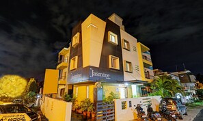 Un immeuble à plusieurs étages portant l’enseigne « Jasmine Suites », ce qui indique qu’il s’agit d’un hôtel.