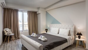 Una habitación de hotel moderna con una cama grande, dos mesitas de noche, una silla y vistas a la ciudad.