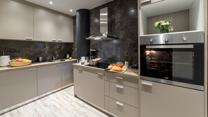 Una cocina moderna con horno empotrado, extractor de acero inoxidable y una isla grande con pileta y encimera.