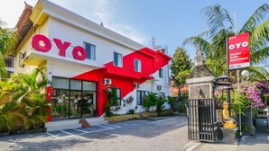 Un edificio con una fachada destacada en rojo y blanco, una entrada con portón y un letrero que indica que es un Apartamento Suite Marina.