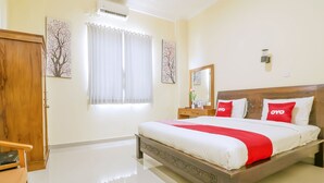 Una habitación de hotel con una cama grande, un cabecero de madera, una mesita de noche y un espejo.