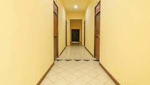 Un pasillo largo y estrecho con pisos de baldosas y puertas de madera a ambos lados.