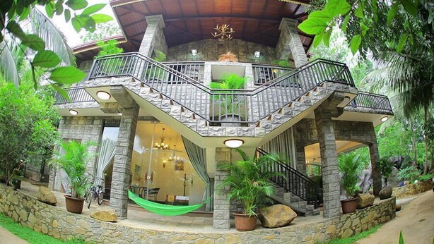 A two-story building with a stone facade, a balcony, and a hammock. - Thevni Holiday Resort (Ingiriya)