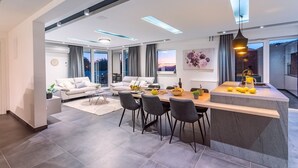 Una sala de estar moderna con comedor, ventanas amplias y una cocina con isla central.