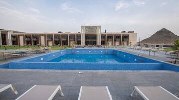 Alberca al aire libre, sombrillas en la alberca y camastros