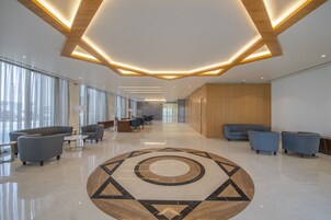 Un vestíbulo amplio con un diseño geométrico en el suelo, asientos modernos y un mostrador de recepción de madera.