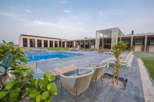Una piscina al aire libre, sombrillas, sillones reclinables de piscina
