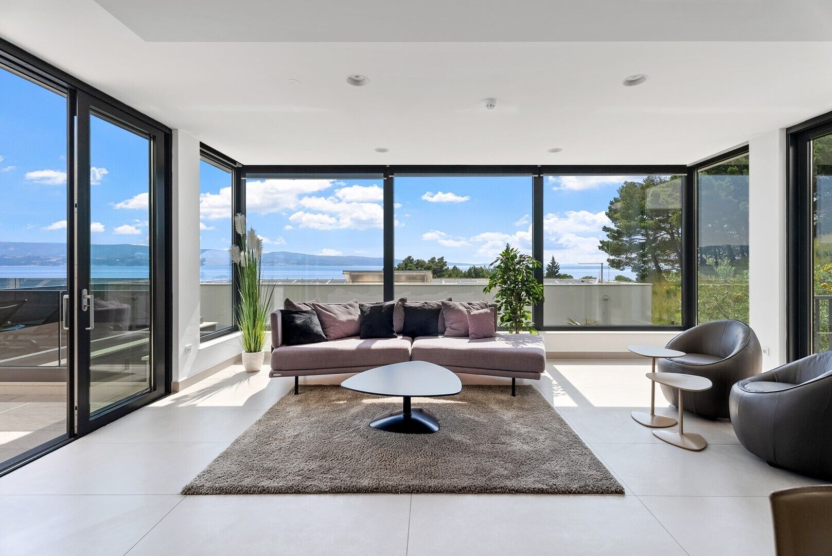 Ein modernes Wohnzimmer mit großem Fenster, einer Couch, einem Couchtisch und Meerblick.