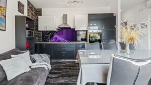 A modern kitchen with a central island, built-in appliances, and a dining area with a glass table and chairs.