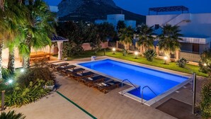 A swimming pool with lounge chairs, a gazebo, and a mountain view.