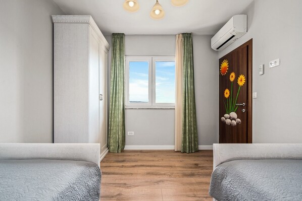 A room with two beds, a window with curtains, an air conditioning unit, and a door with a floral decoration. - Villa Antura with private heated 50sqm pool, 3 bedrooms, 3 bathrooms, and gym (Zrnovnica)