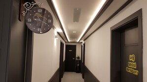 A hallway with a clock, doors, and a sign reading "seoul dormitory". - We Home Guesthouse - Hostel (Incheon)