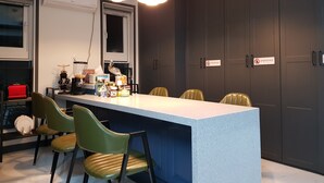A modern kitchen with a central island, green chairs, and pendant lighting. - We Home Guesthouse - Hostel (Incheon)