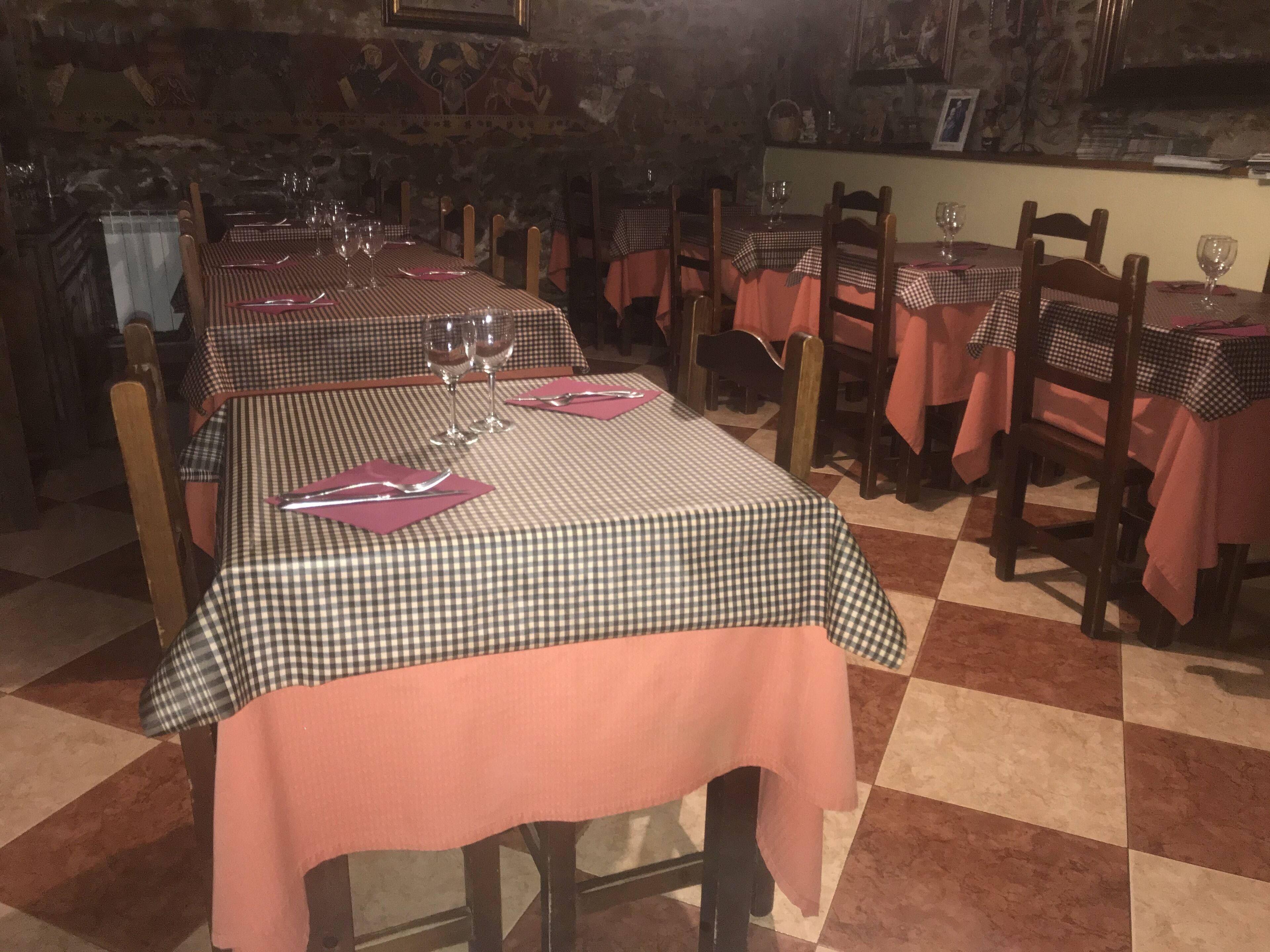 Een restaurant met geruite tafelkleden, houten stoelen en wijn glazen, klaar om te dineren.