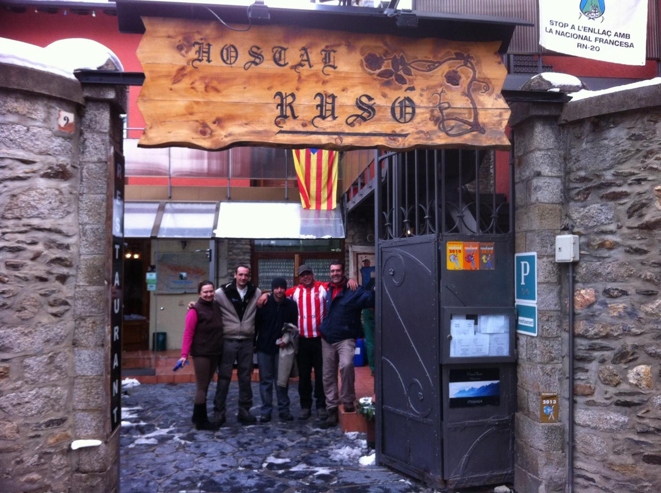 Un letrero de madera con el nombre "Hostal Ruso" sobre una entrada de piedra.