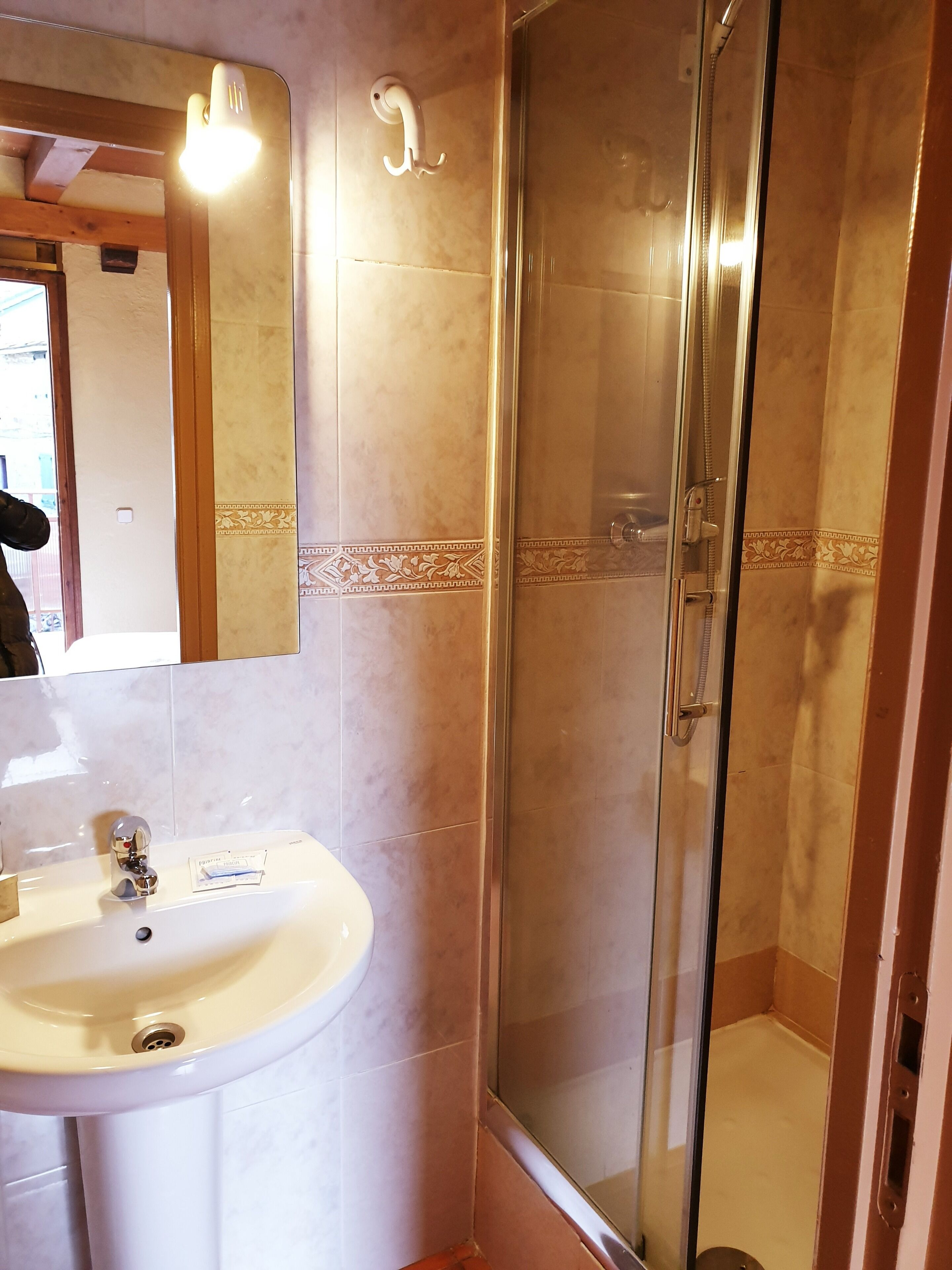 A bathroom with a sink, mirror, and glass shower enclosure.