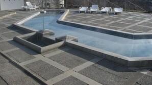 A swimming pool with a stone wall and lounge chairs. - Hostal Ruso (Llívia)